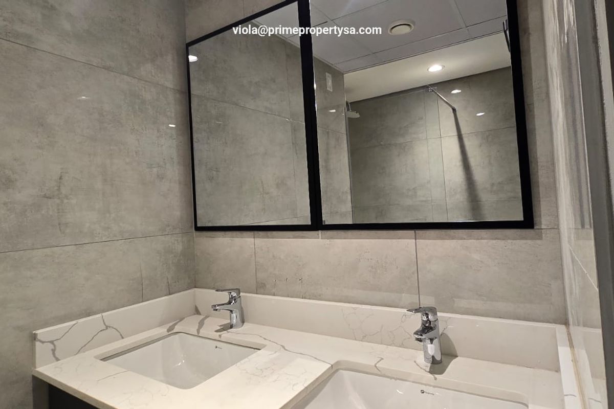 Modern bathroom featuring a double vanity with quartz countertops, undermount sinks, chrome fixtures, and large format grey wall tiles.