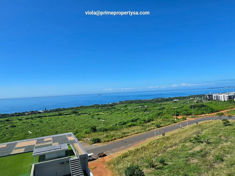 An elevated panoramic view overlooking the coastline, surrounding greenery, and local road infrastructure.