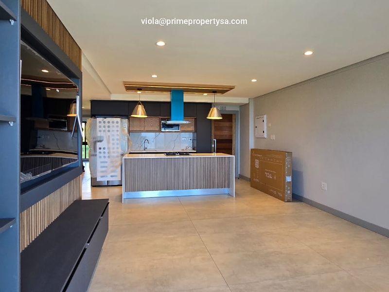 Modern open-plan living and kitchen area featuring a central island, sleek cabinetry, recessed lighting, and large format floor tiles in a contemporary apartment.