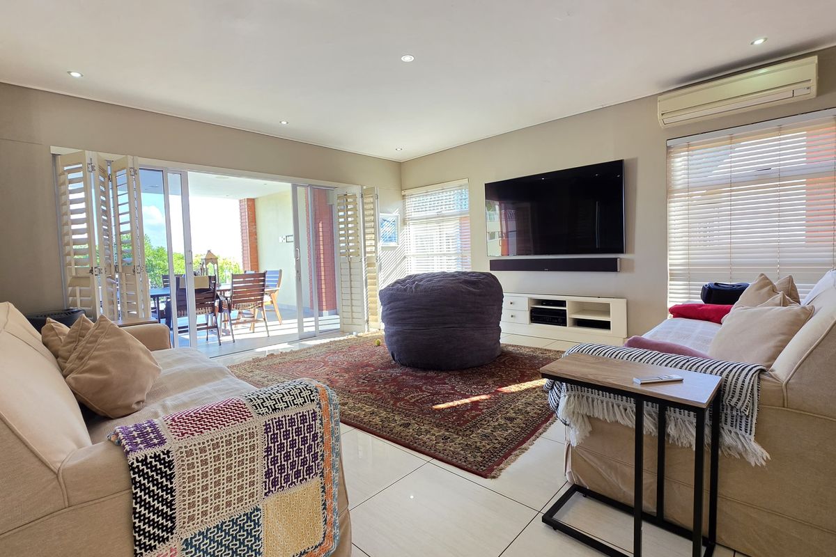 Spacious living room featuring tiled flooring, recessed lighting, split-system air conditioning, and large sliding glass doors opening to an outdoor patio area.