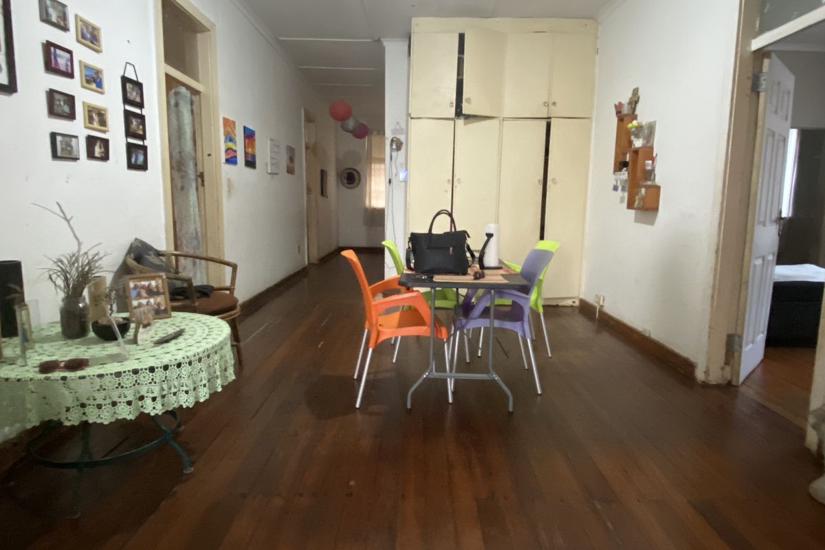 A living area featuring original timber flooring and built-in storage cabinetry, offering a functional space with potential for cosmetic updates.