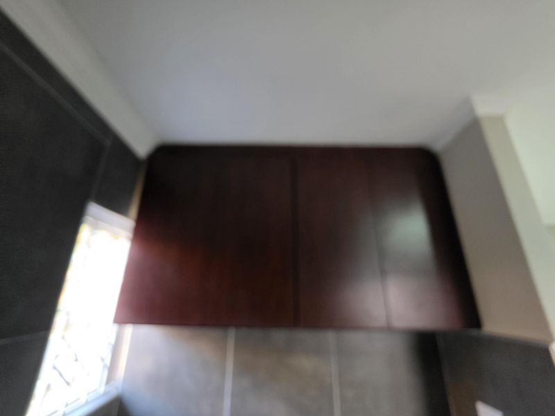 A close-up view of dark wood kitchen cabinetry mounted above a tiled splashback area.