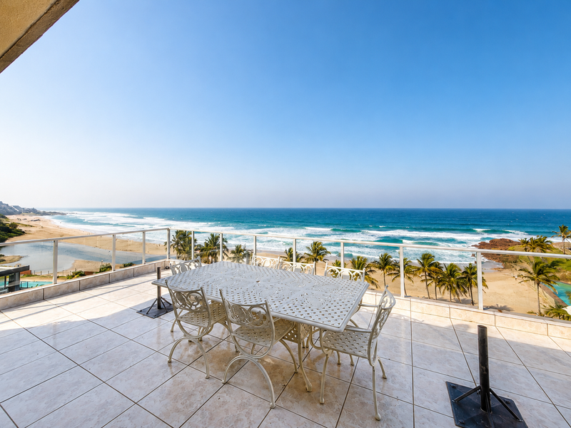 Spacious balcony featuring tiled flooring and a glass balustrade, offering expansive, unobstructed views of the ocean and coastline.