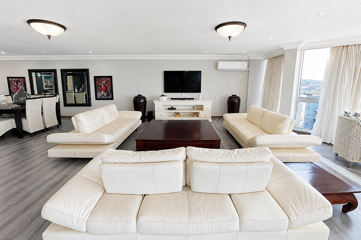 Spacious living room featuring modern laminate flooring, recessed lighting, crown molding, and a wall-mounted air conditioning unit with large windows providing natural light.