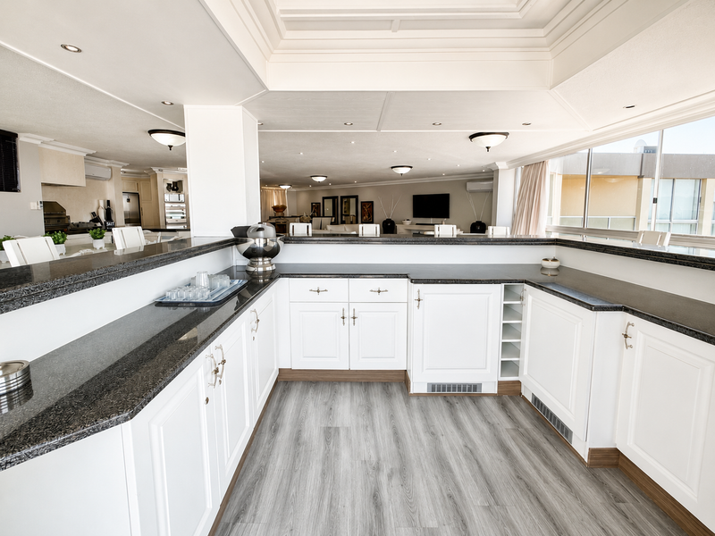 Spacious open-plan living area featuring a well-appointed kitchen with granite countertops, white cabinetry, and a breakfast bar, complemented by modern tray ceilings.