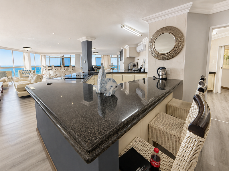 Spacious open-plan living and kitchen area featuring granite countertops, modern cabinetry, and expansive windows offering panoramic ocean views.