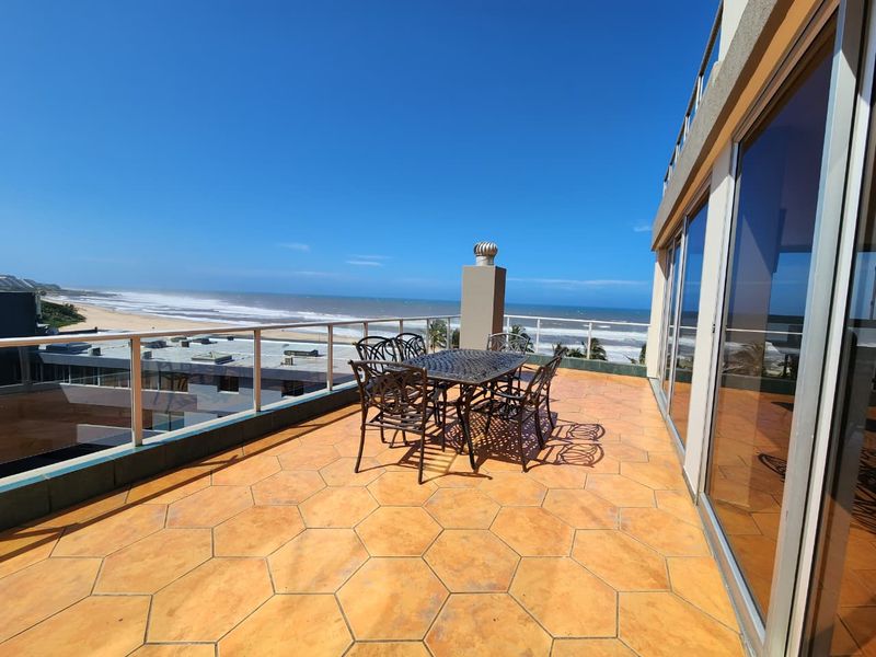 Spacious balcony featuring hexagonal tiled flooring, a glass balustrade, and expansive ocean views, accessible via large sliding glass doors.