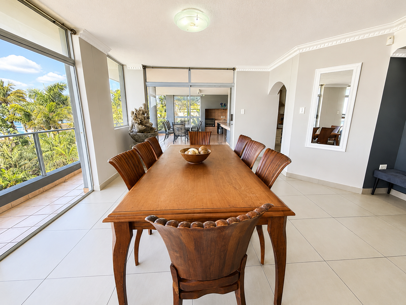 Spacious dining area featuring large sliding glass doors that open to a balcony, tiled flooring, and elegant crown molding throughout the space.