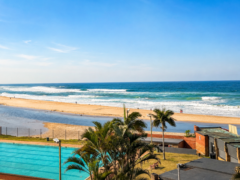 A scenic elevated view overlooking a swimming pool, coastal landscape, and the ocean beach.