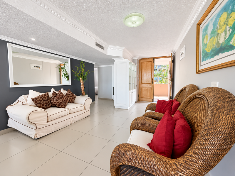 Spacious living area featuring tiled flooring, crown molding, built-in cabinetry, and direct access to an outdoor balcony through a timber door.