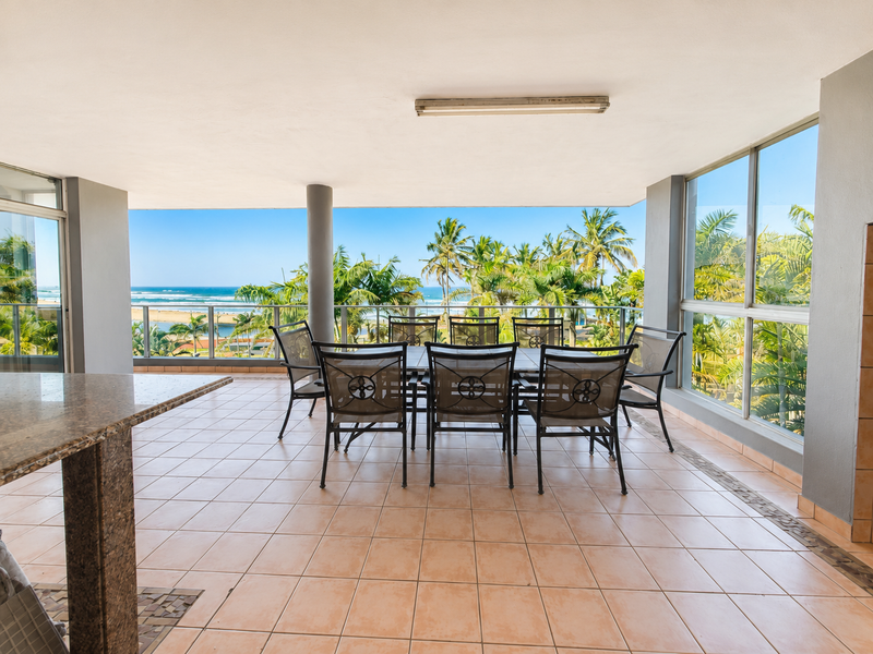 Spacious covered balcony featuring tiled flooring, a built-in granite breakfast bar, and expansive ocean views, perfect for outdoor dining and relaxation.