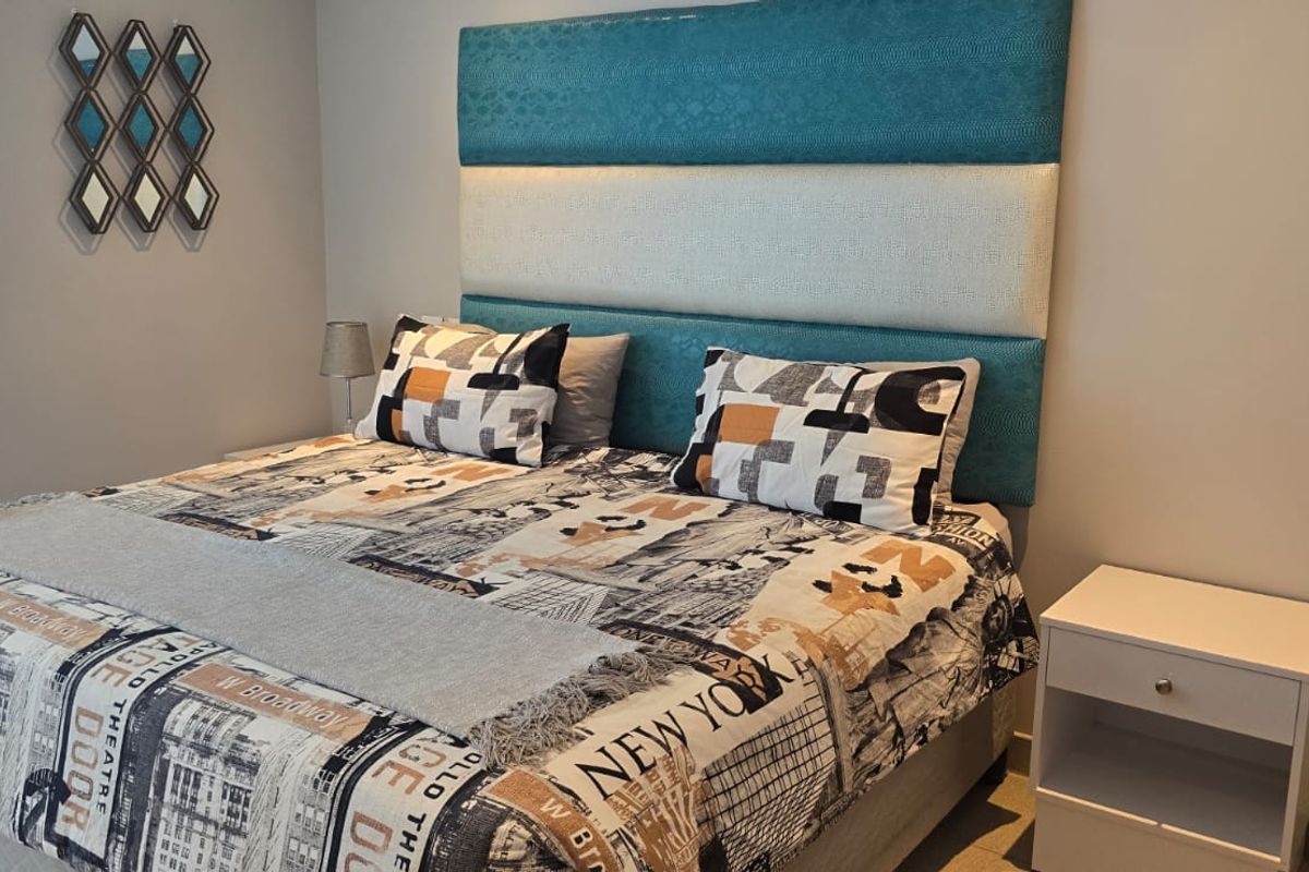A well-maintained bedroom featuring a modern upholstered headboard and functional roller blinds, providing a clean and comfortable living space.
