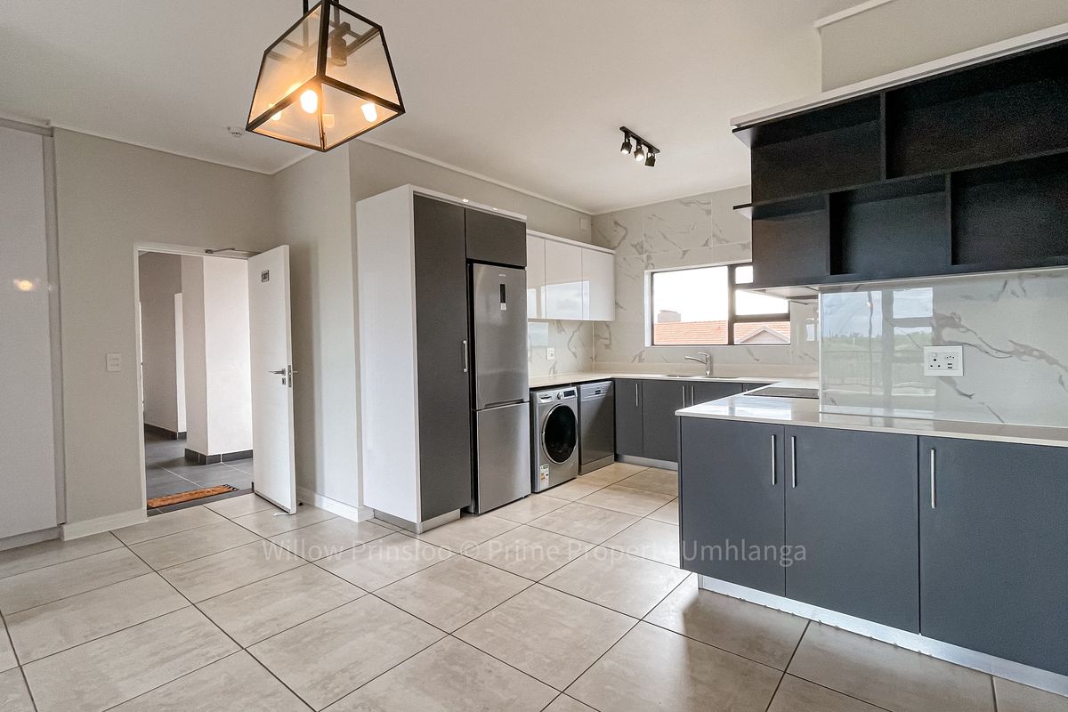 Modern kitchen featuring sleek grey and white cabinetry, marble-look splashbacks, integrated appliances, and contemporary lighting fixtures in an open-plan layout.