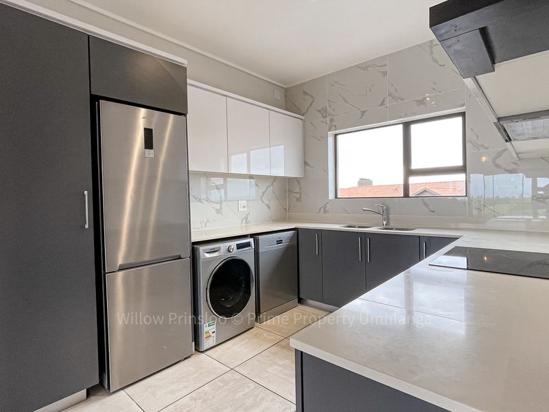 Modern kitchen featuring sleek grey and white cabinetry, stone countertops, marble-look splashbacks, and integrated stainless steel appliances.