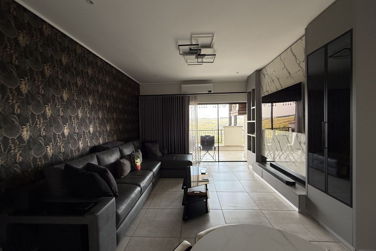 Modern living room featuring tiled floors, a custom built-in media wall, recessed lighting, and direct access to a balcony with scenic views.
