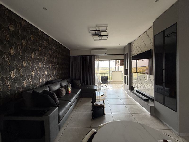 Modern living room featuring tiled floors, a custom built-in media wall, recessed lighting, and direct access to a balcony with scenic views.