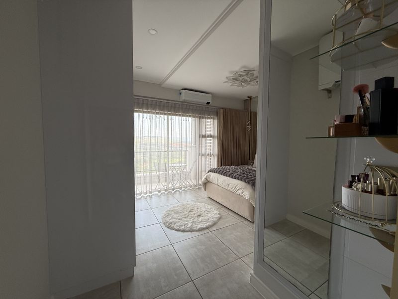 Modern bedroom featuring tiled floors, built-in cupboards, air conditioning, and a sliding glass door leading to a private balcony.