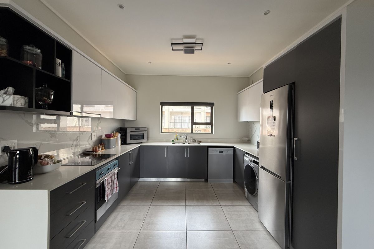 Modern kitchen featuring sleek two-tone cabinetry, stone countertops, integrated appliances, and high-quality tiled flooring in a clean, contemporary layout.
