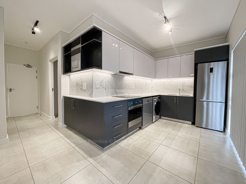 Modern kitchen featuring sleek two-tone cabinetry, marble-look splashback, integrated appliances, and high-quality tiled flooring in an open-plan layout.