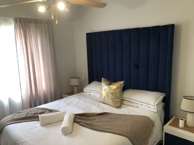 A well-maintained bedroom featuring a ceiling fan and neutral wall finishes, providing a comfortable and functional sleeping space.