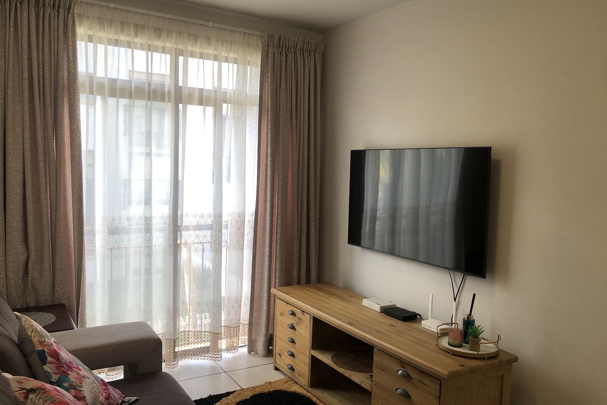 A well-maintained living room featuring tiled flooring and a large sliding glass door that provides access to the balcony.