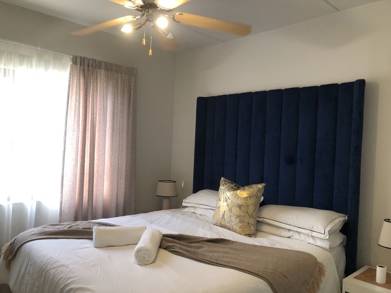 A well-maintained bedroom featuring a ceiling fan and neutral wall finishes, providing a comfortable and functional sleeping space.