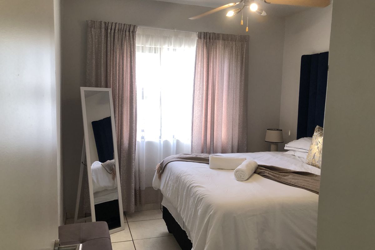 A well-lit bedroom featuring tiled flooring and a ceiling fan, providing a comfortable and functional living space.