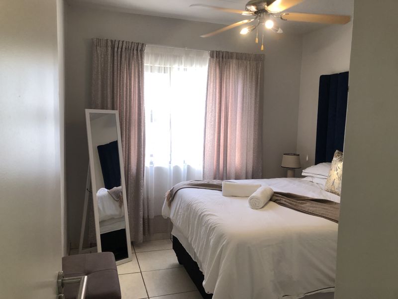 A well-lit bedroom featuring tiled flooring and a ceiling fan, providing a comfortable and functional living space.