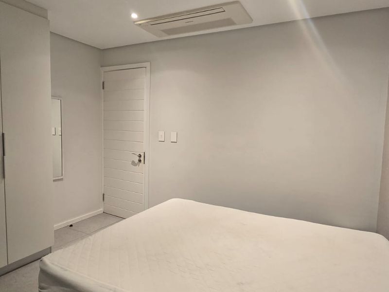A modern bedroom featuring built-in cupboards, tiled flooring, and a recessed ceiling air conditioning unit.
