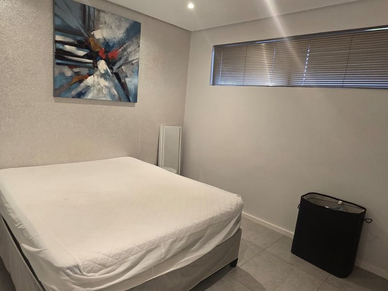 A well-maintained bedroom featuring tiled flooring, recessed downlighting, and a built-in wardrobe with horizontal window blinds.