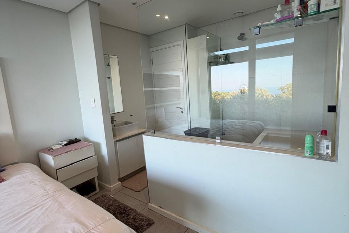 Modern bedroom featuring tiled flooring, recessed lighting, ducted air conditioning, and an open-plan en-suite bathroom separated by a glass partition wall.