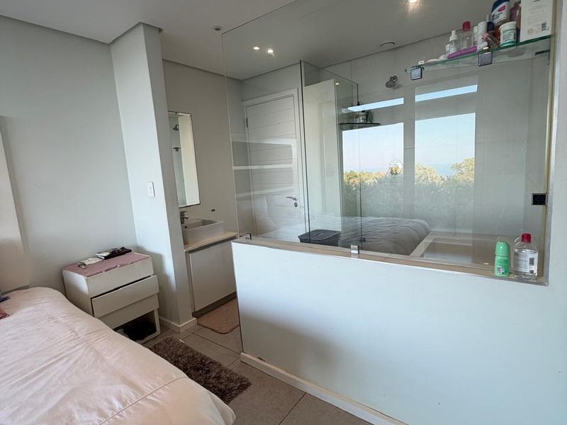 Modern bedroom featuring tiled flooring, recessed lighting, ducted air conditioning, and an open-plan en-suite bathroom separated by a glass partition wall.