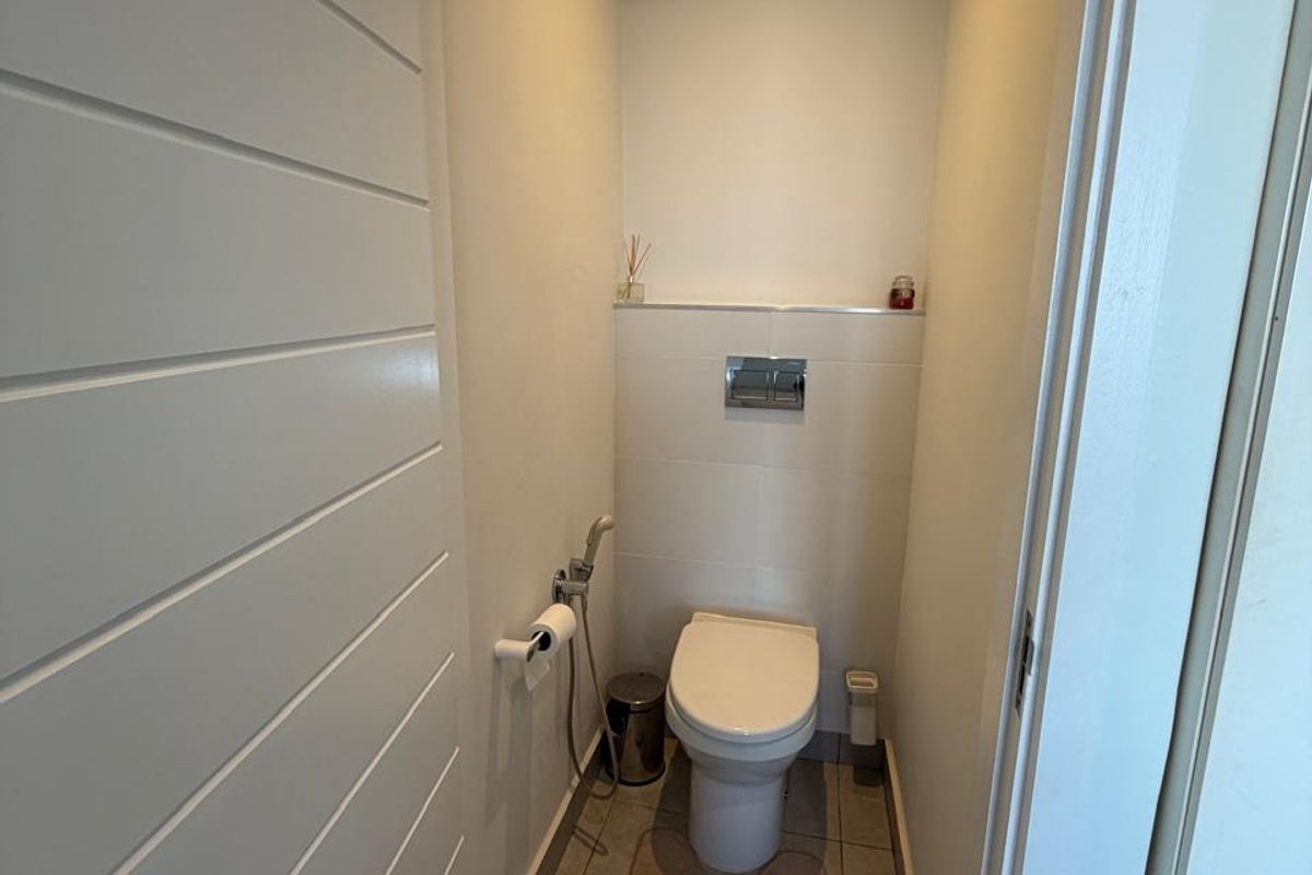 A compact, modern guest bathroom featuring a wall-mounted toilet with a concealed cistern and neutral floor tiling.