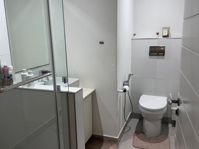 Modern bathroom featuring a glass-enclosed shower, wall-mounted toilet with concealed cistern, and a vanity basin with neutral floor tiling.