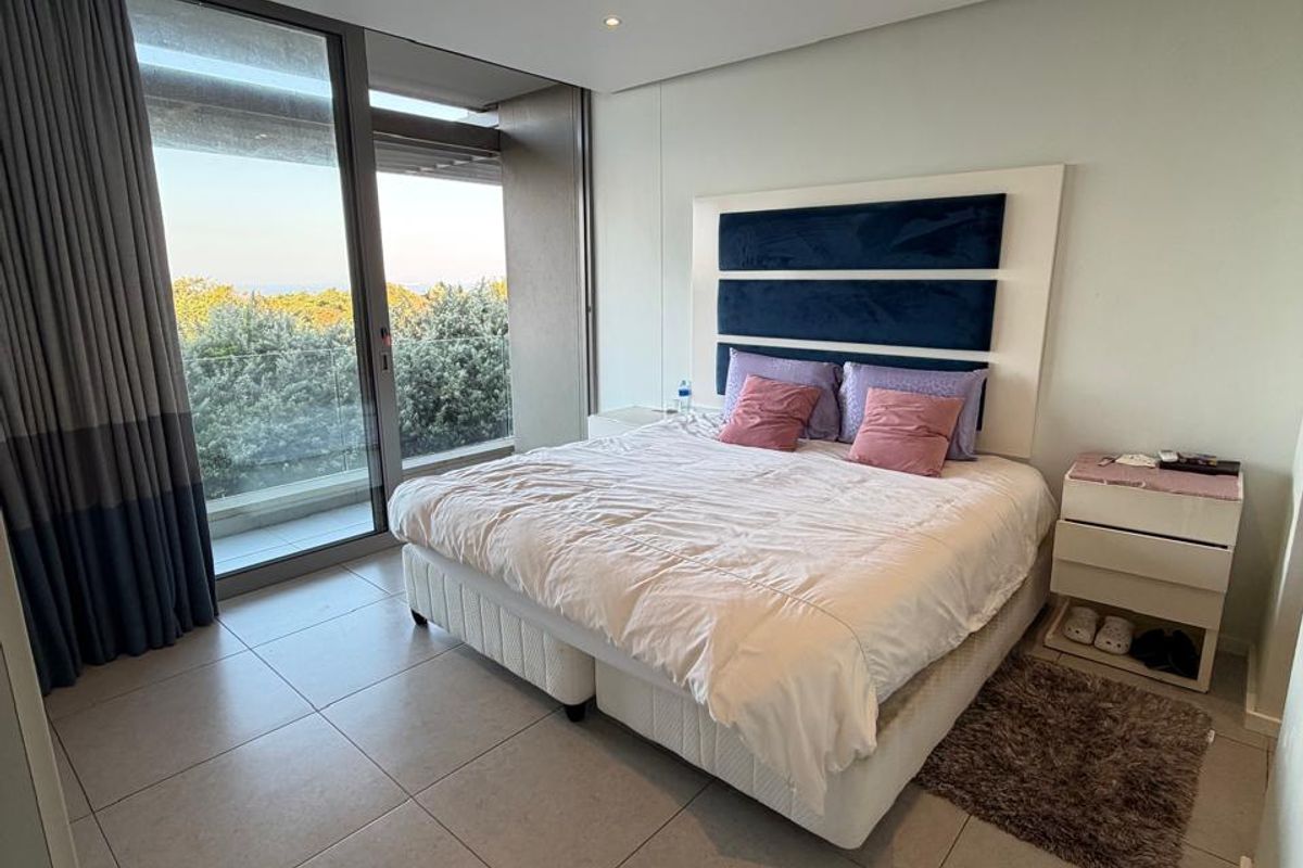 A modern bedroom featuring large floor-to-ceiling sliding glass doors, tiled flooring, recessed lighting, and integrated ducted air conditioning.