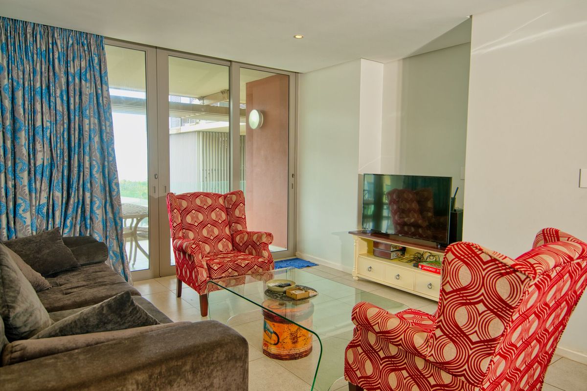 A bright living room featuring large sliding glass doors that provide access to an outdoor balcony and allow for ample natural light.