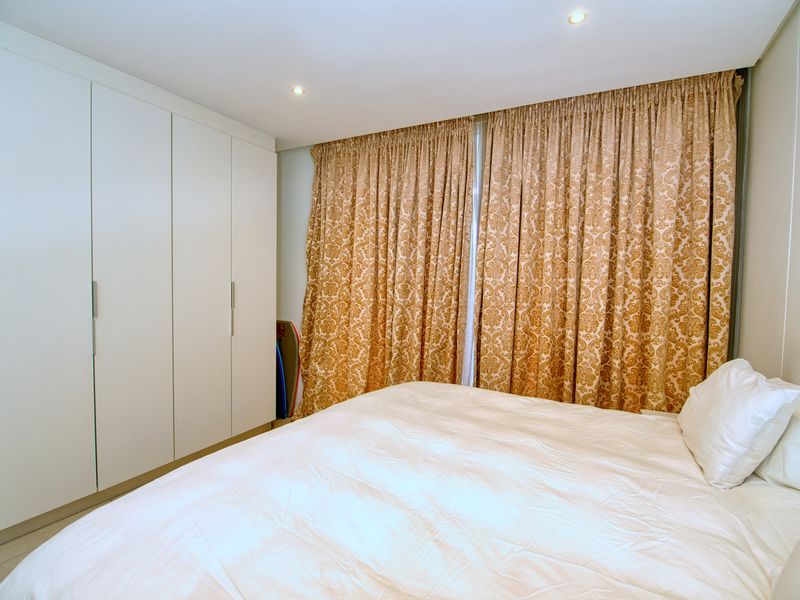 A well-maintained bedroom featuring floor-to-ceiling built-in cupboards and recessed downlighting, providing ample storage and a clean, functional layout.