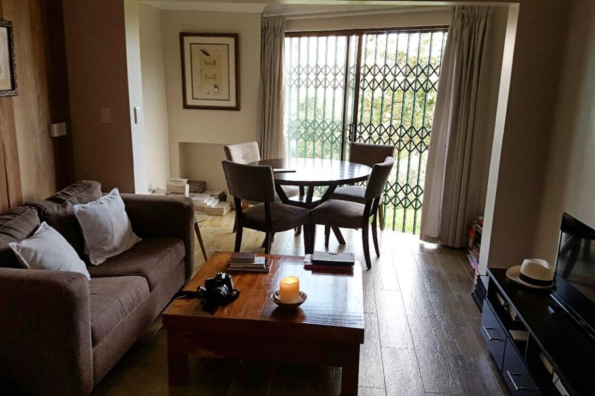 A comfortable living room featuring laminate flooring and a sliding glass door with a security gate, providing access to the outdoors.