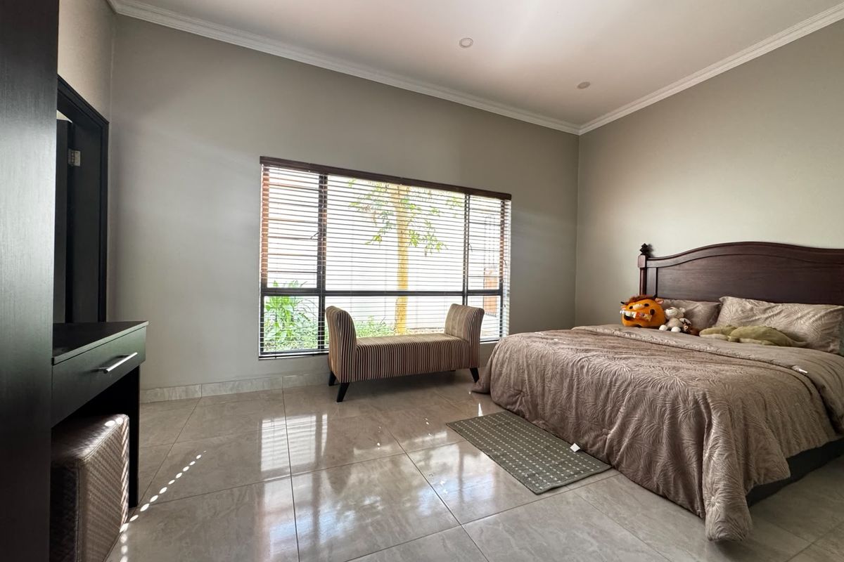 Spacious bedroom featuring large windows with venetian blinds, polished tile flooring, recessed lighting, and a built-in vanity unit.