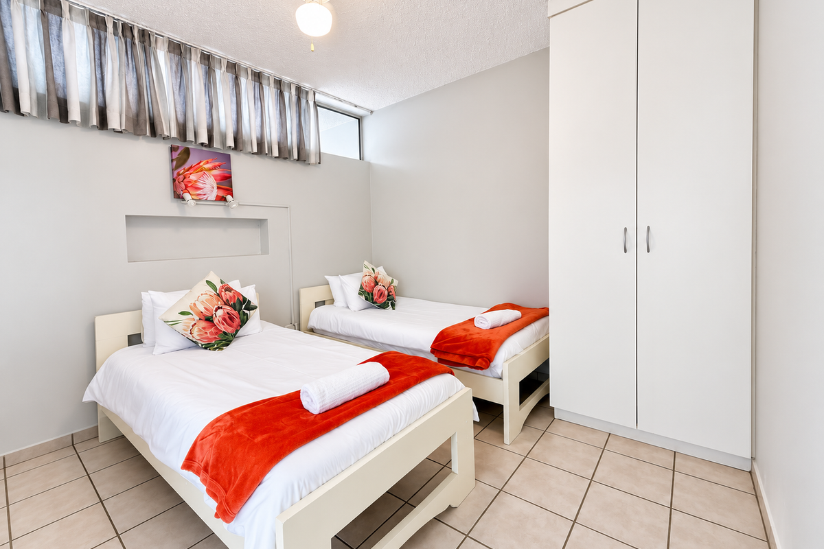A functional bedroom featuring tiled flooring, a built-in wardrobe, and a recessed wall niche, providing a clean and practical living space.
