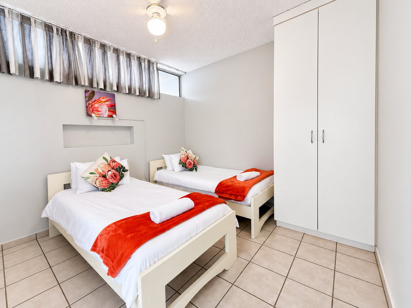 A functional bedroom featuring tiled flooring, a built-in wardrobe, and a recessed wall niche, providing a clean and practical living space.