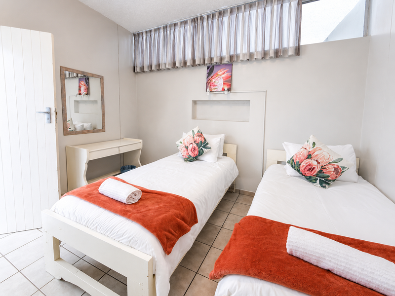 A functional bedroom featuring tiled flooring, a built-in wall niche, and high-level clerestory windows providing natural light.