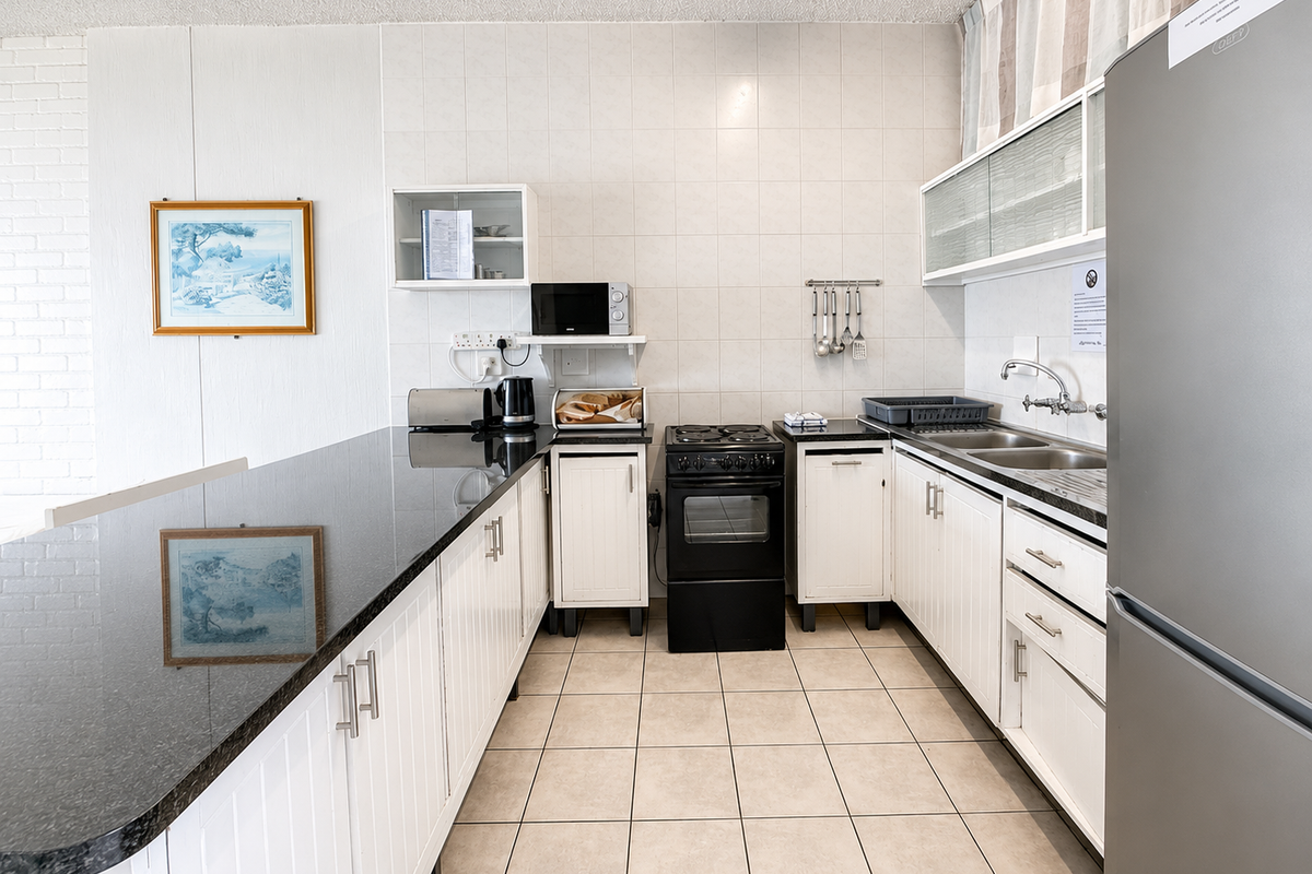 A functional kitchen featuring white cabinetry, granite countertops, a tiled backsplash, and a freestanding electric stove with ample storage space.