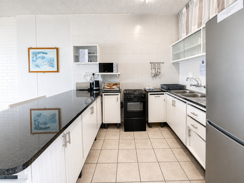 A functional kitchen featuring white cabinetry, granite countertops, a tiled backsplash, and a freestanding electric stove with ample storage space.