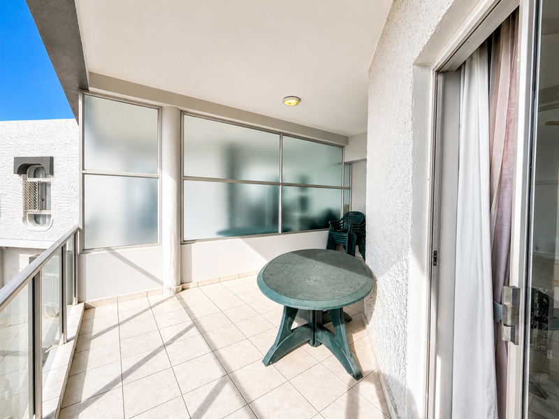 A covered balcony featuring tiled flooring, a glass balustrade, and a frosted glass privacy screen, providing a functional outdoor space.