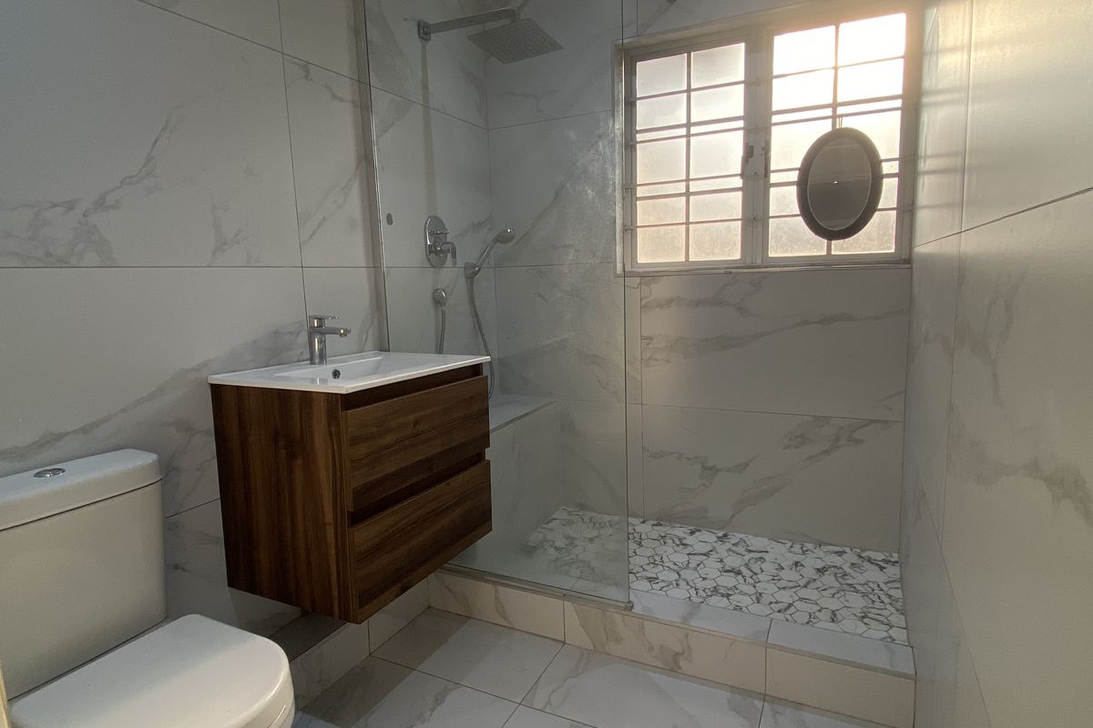 Modern bathroom featuring a walk-in shower with glass screen, wall-mounted vanity, and contemporary marble-look tiling throughout.
