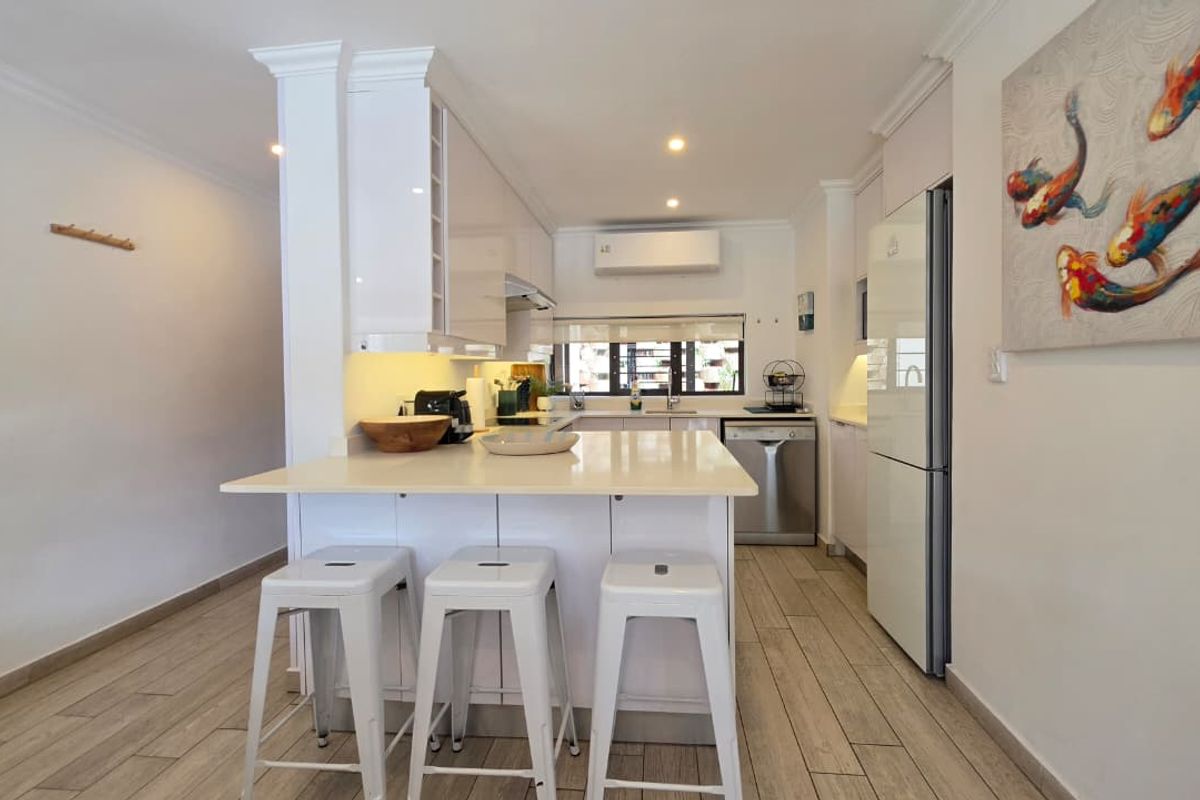 Modern kitchen featuring gloss white cabinetry, quartz countertops, a breakfast bar, and wood-look tile flooring, complemented by integrated lighting and air conditioning.