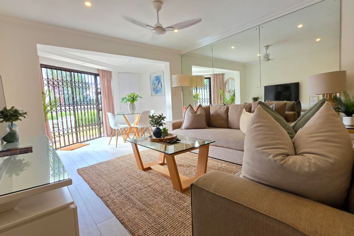 A bright living room featuring tiled flooring, a large mirrored wall, recessed lighting, and a ceiling fan, with direct access to an outdoor area.