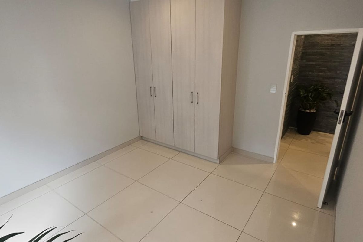 A clean, empty bedroom featuring neutral tiled flooring and modern built-in cupboards, offering a versatile space ready for personalization.