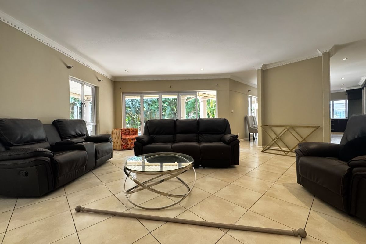Spacious living room featuring neutral tiled flooring, recessed downlighting, decorative crown molding, and large sliding glass doors providing access to the outdoor area.